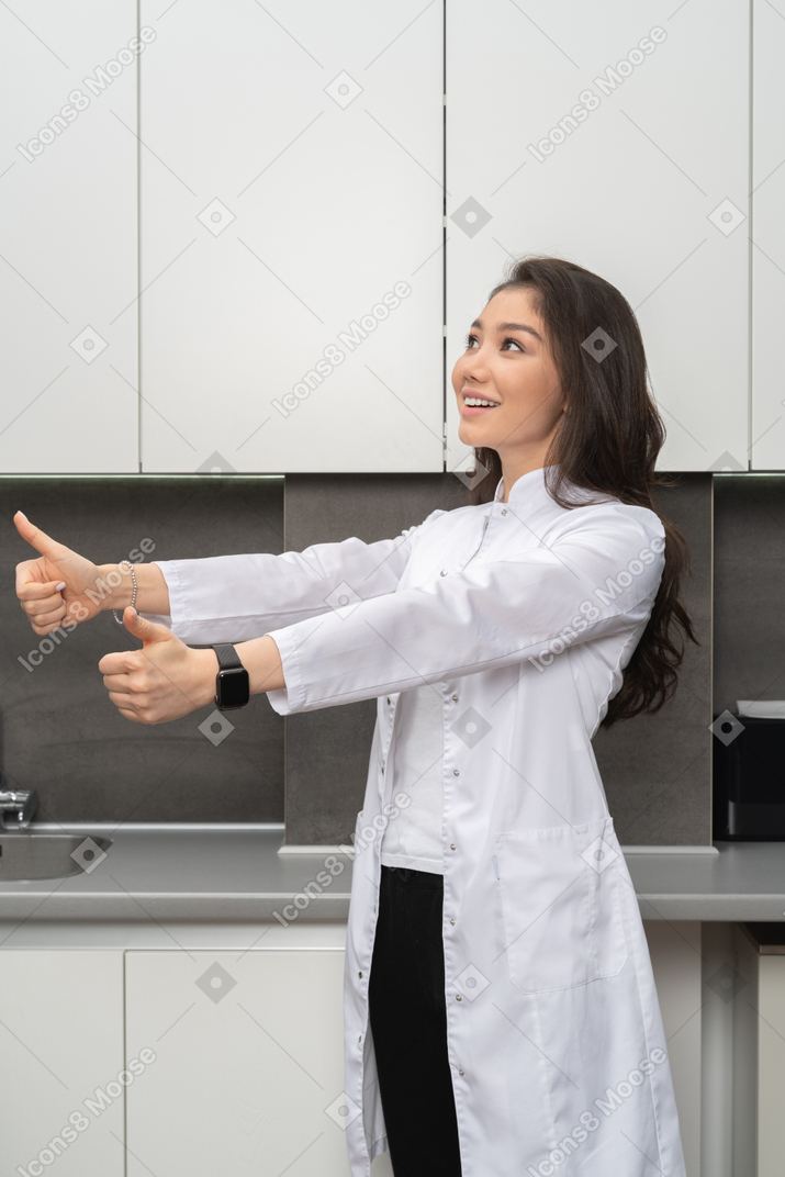 Eine lächelnde krankenschwester, die sich mit beiden händen wie eine geste zeigt