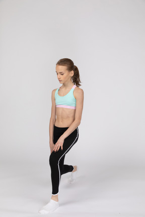 Three-quarter view of a teen girl in a sportswear making a lunge