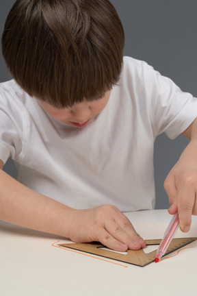 Menino asiático desenhando formas geométricas usando régua triangular