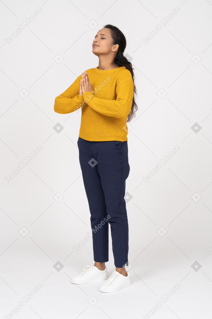 Side view of a girl in casual clothes making praying gesture