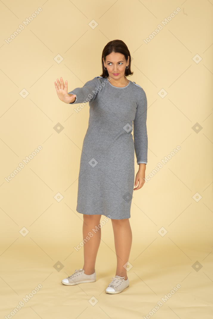 Vista frontal de uma mulher de vestido cinza mostrando a placa de pare