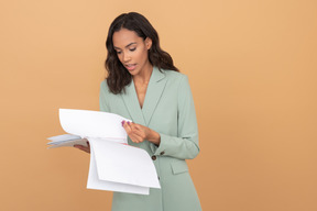 Beautiful businesswoman folding papers and saying something