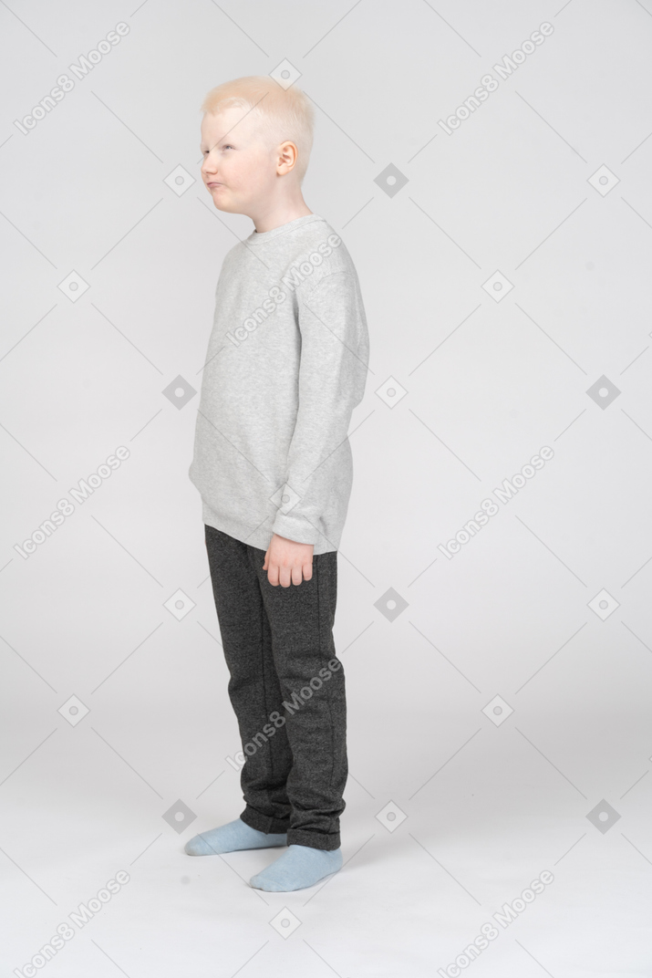 В полный рост маленький мальчик в повседневной одежде дразнит