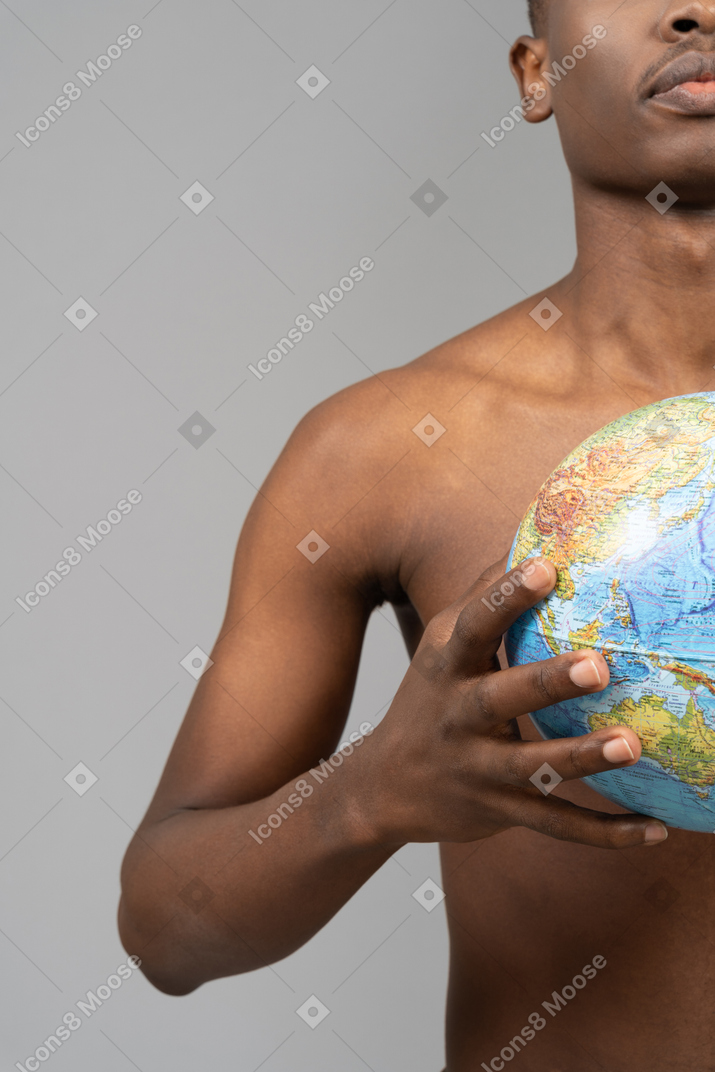 A shirtless young man holding the earth globe