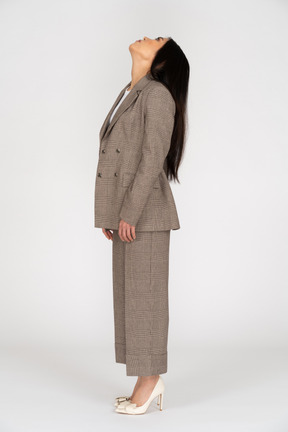Side view of a young lady in brown business suit throwing head back