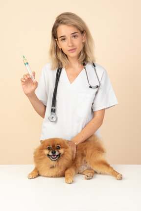 Attractive veterenarian ready to make an injection to a red spitz