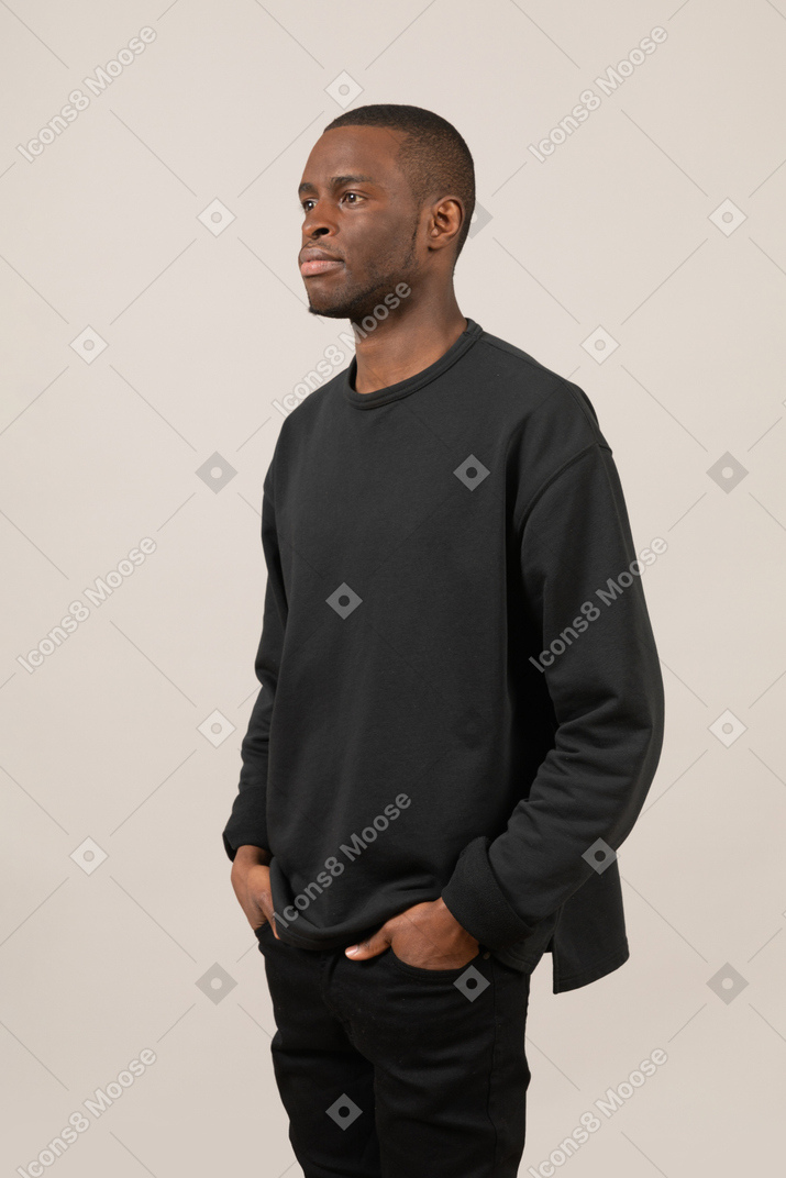 Young man keeping hands in pockets and looking away