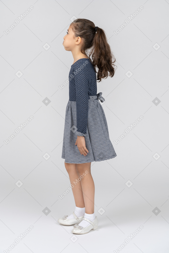 Side view of a girl in casual clothing with puffed out cheeks