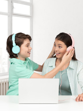 Niño poniendo auriculares en la cabeza de una mujer