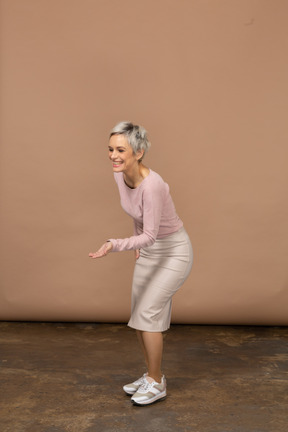 Vista lateral de una mujer en ropa casual haciendo gesto de bienvenida