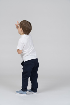 Back view of little boy raising his hands