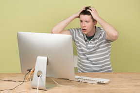 Terrified young man touching his head