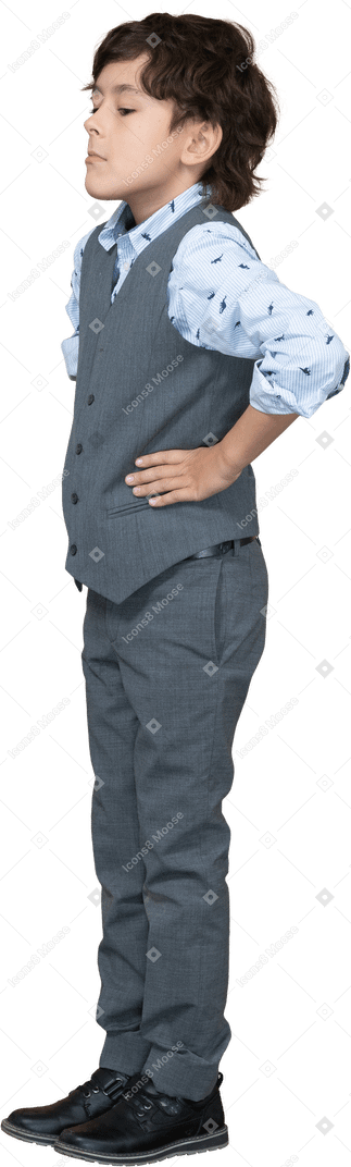 Side view of a boy in suit posing with hands on hips