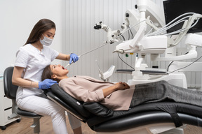 Longitud total de una dentista examinando a su paciente acostada en un gabinete de hospital