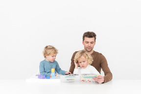 Pai jogando e lendo com seus filhos