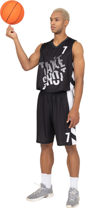 Vista de tres cuartos de un joven jugador de baloncesto masculino sosteniendo una pelota