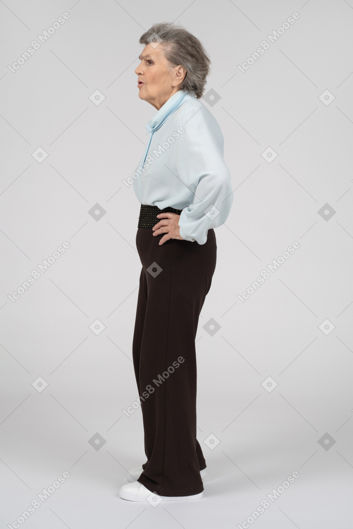 Side view of a frowning old woman with a hand on the hip