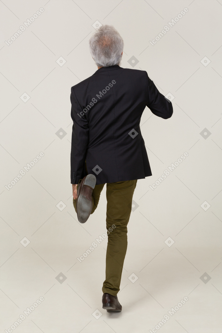 Vista traseira de um homem em uma jaqueta em pé em uma perna