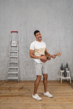 Three-quarter view of a man singing and playing ukulele