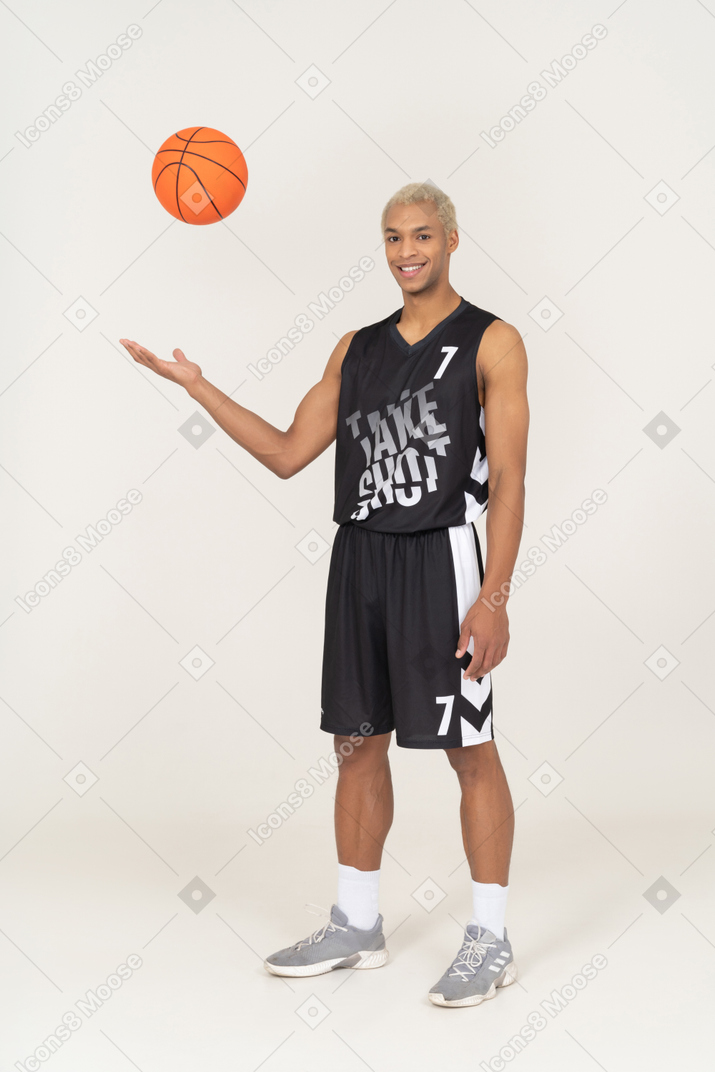 Vista de tres cuartos de un joven jugador de baloncesto masculino lanzando una pelota