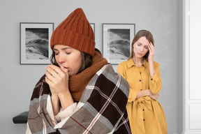 A woman wrapped in blanket and warm clothes having a cold