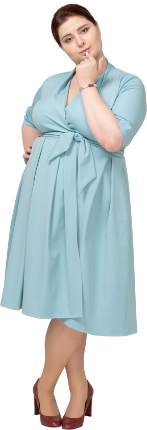 Vista frontal de uma mulher de vestido azul mordendo o dedo