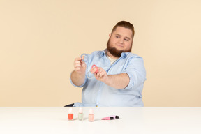 Big man looking attentively at hair bands he's holding