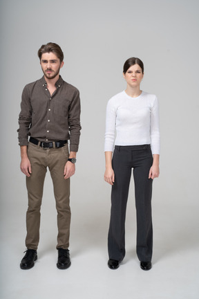 Front view of a displeased young couple in office clothing knitting brows