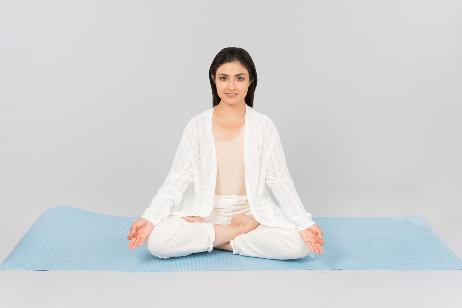 Indian woman sitting with legs crossed on yoga mat