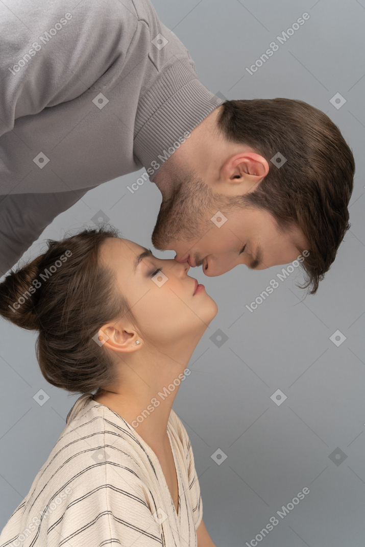 Young man leaning over his girlfriend and kissing her nose