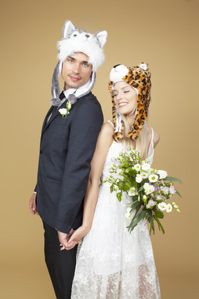 Groom and bride wearing animal hats and holding hands