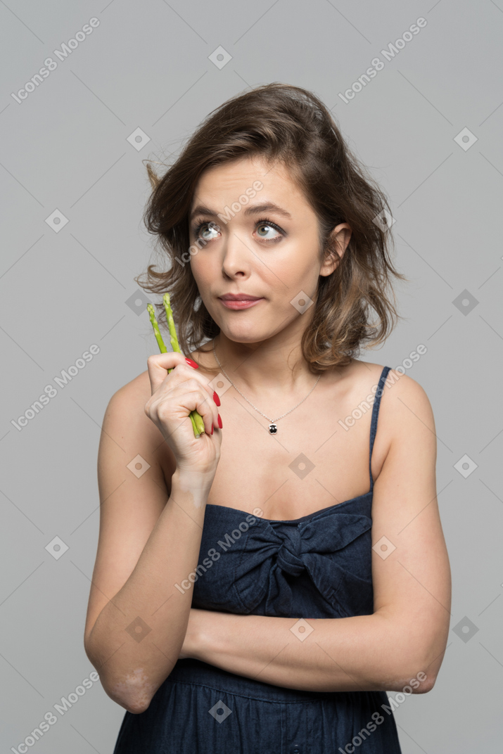 Thoughtful young woman with asparagus