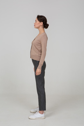 Side view of a young lady in pullover and pants standing with her eyes closed