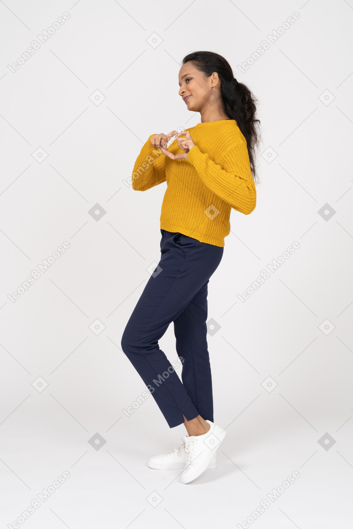 Vista lateral de uma garota com roupas casuais, mostrando o sinal do coração