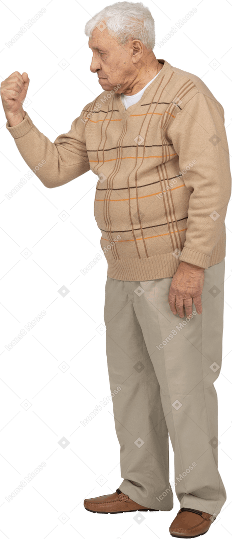 Side view of an old man in casual clothes showing fist
