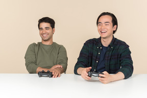 Amigos interraciales sentados a la mesa y jugando videojuegos