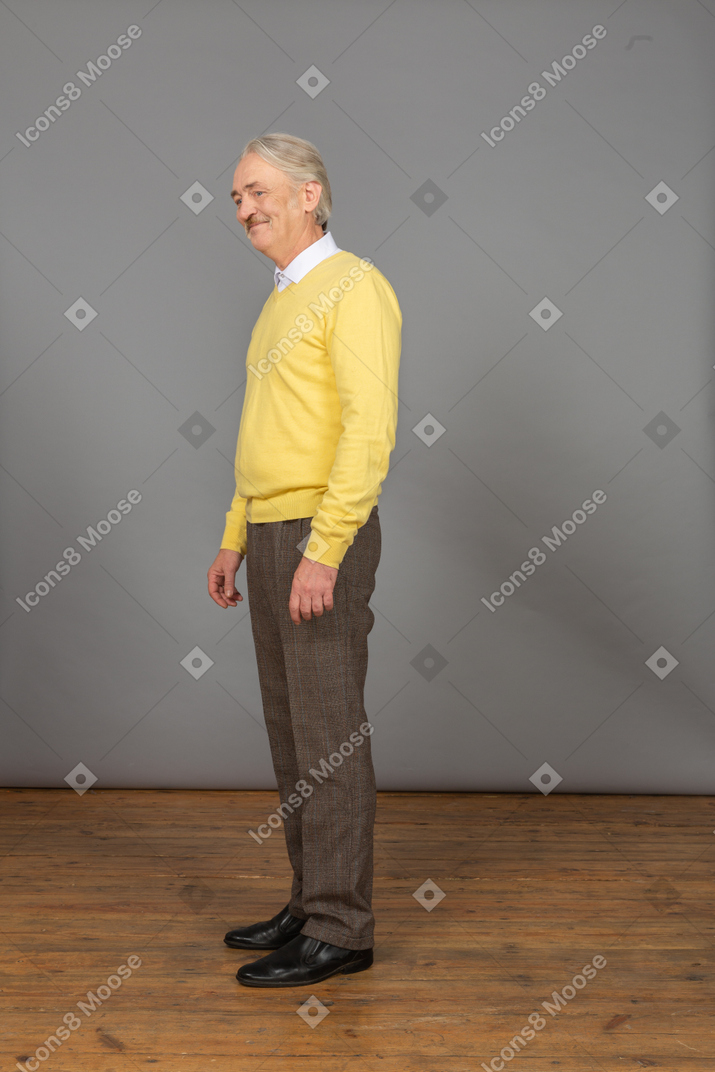 Three-quarter view of a smiling old man in yellow pullover and looking aside