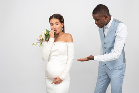 Marié pointant sur le ventre de sa mariée alors qu'elle a l'air choqué