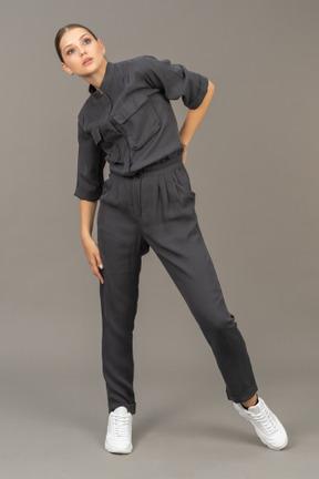 Front view of a young woman in a jumpsuit putting hand on waist