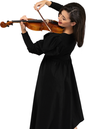 Close-up of a young cheerful lady in black dress playing the violin