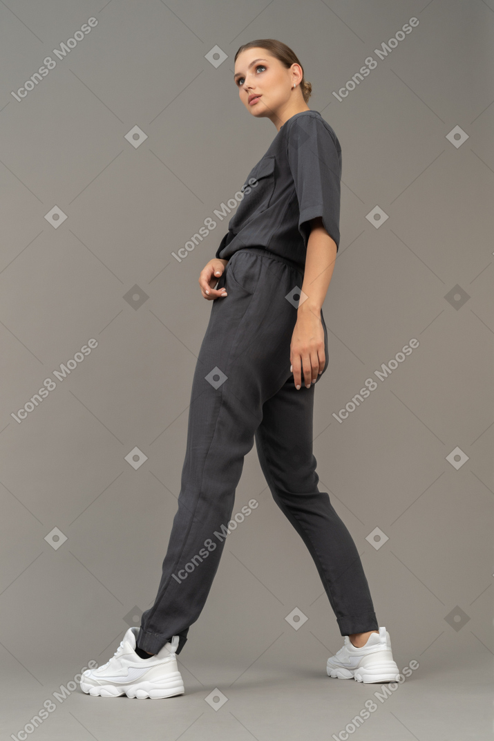 一个穿着连身裤的专横的年轻女人的侧视图