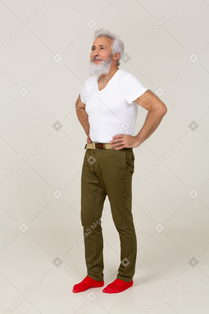 Hopeful man in casual clothes standing with hands on waist