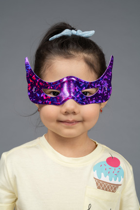 Little girl trying on superhero mask