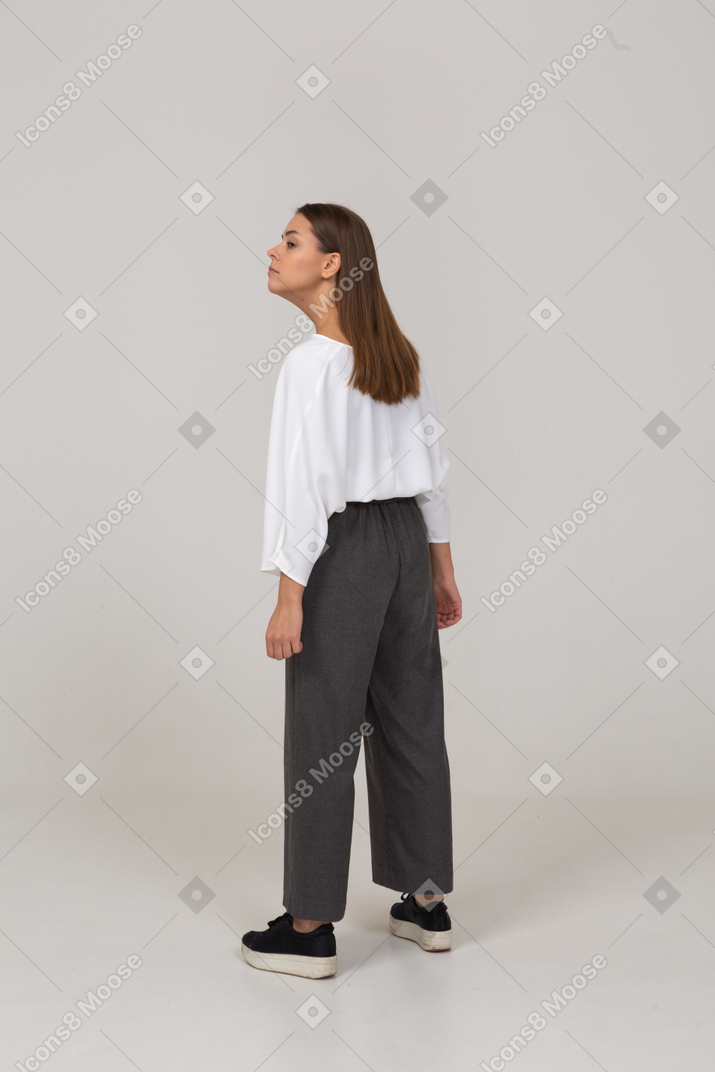 Three-quarter back view of a young lady in office clothing outstretching her neck