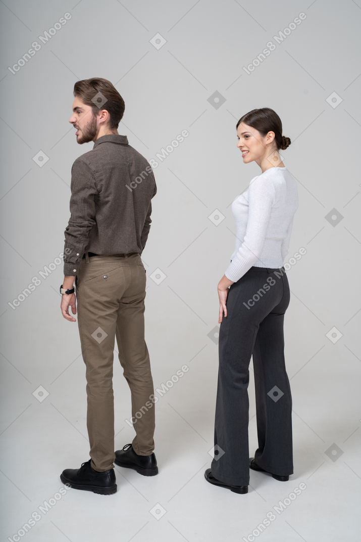 Three-quarter back view of a young couple in office clothing clenching teeth