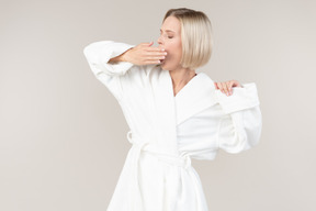 Young woman in bathrobe yawning