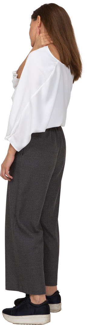 Three-quarter back view of a young lady in office clothing touching neck