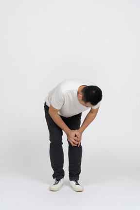 Front view of a man bending down and touching hurting knee