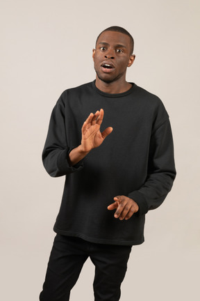 Young man looking worried and reaching arm towards camera