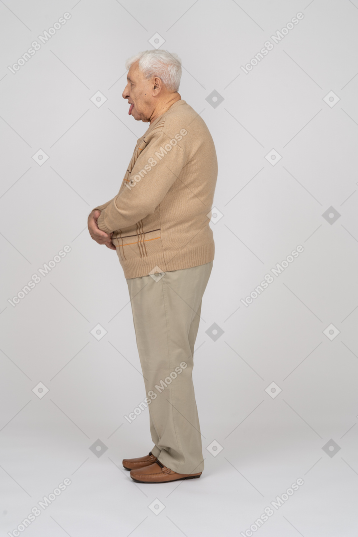 Side view of an old man in casual clothes showing tongue
